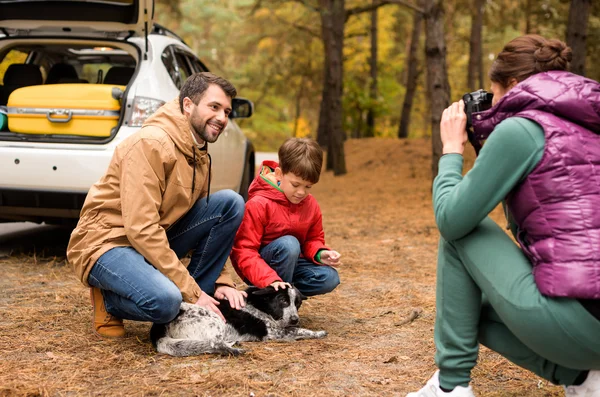 Famille heureuse jouant avec le chien dans la forêt — Photo de stock