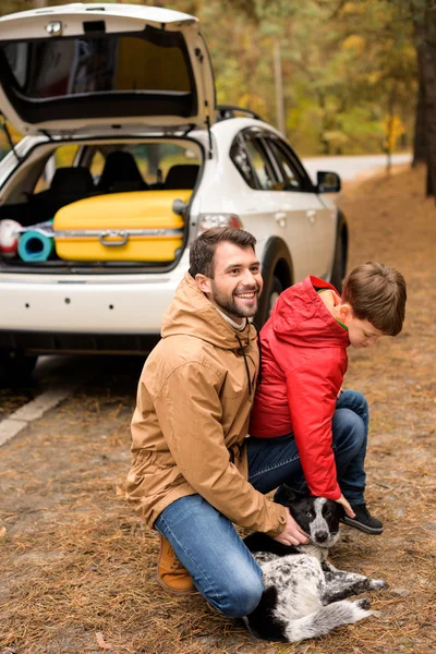 Famille heureuse jouant avec le chien dans la forêt — Photo de stock