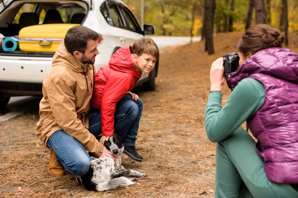 Glückliche Familie spielt mit Hund im Wald — Stockfoto