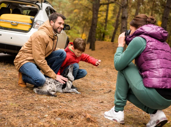 Família feliz brincando com cão na floresta — Fotografia de Stock