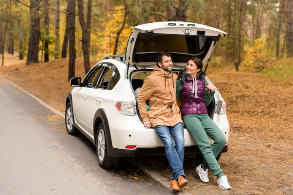 Smiling couple sitting in car trunk — Stock Photo