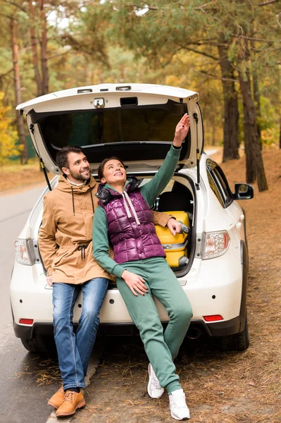 Sorrindo casal sentado no porta-malas do carro — Fotografia de Stock