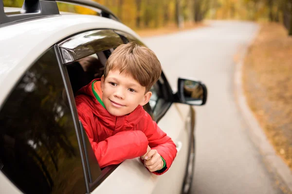 Sonriente chico mirando por la ventana del coche - foto de stock