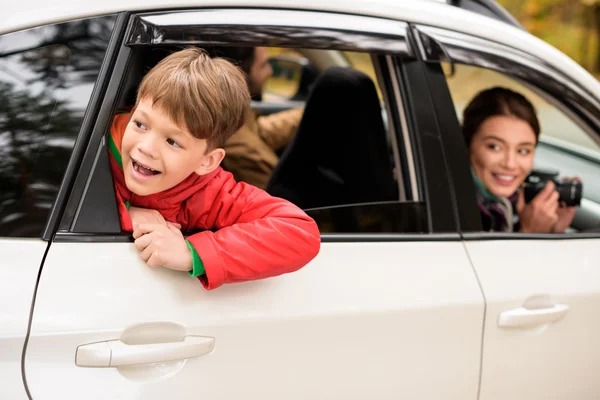 Garçon souriant regardant par la fenêtre de la voiture — Photo de stock