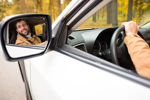 Conducteur souriant reflété dans le miroir de voiture — Photo de stock