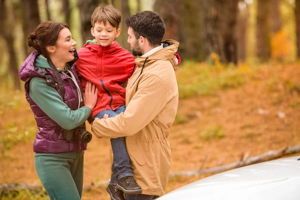 Familia feliz cerca de coche en el bosque - foto de stock