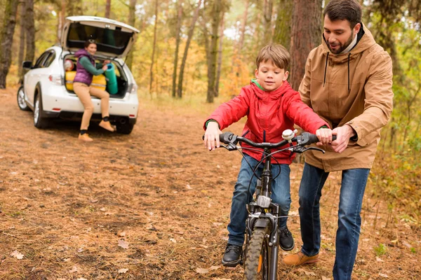 Padre enseñando a su hijo a andar en bicicleta - foto de stock