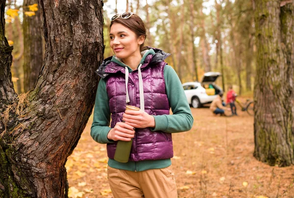 Mujer sonriente con termos en el bosque de otoño - foto de stock