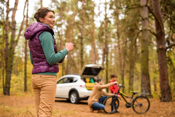 Donna sorridente con thermos nella foresta autunnale — Foto stock