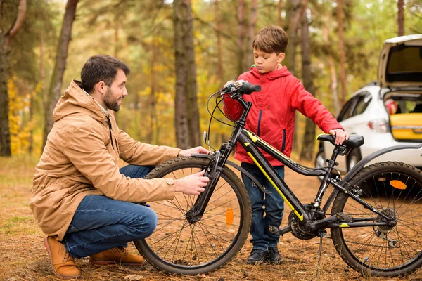 Padre enseñando a su hijo a andar en bicicleta - foto de stock