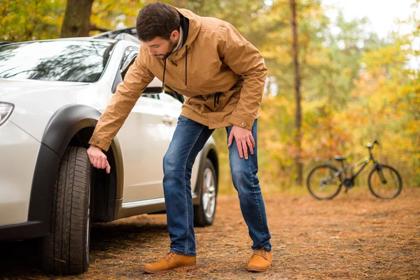 Hombre revisando neumático de coche - foto de stock