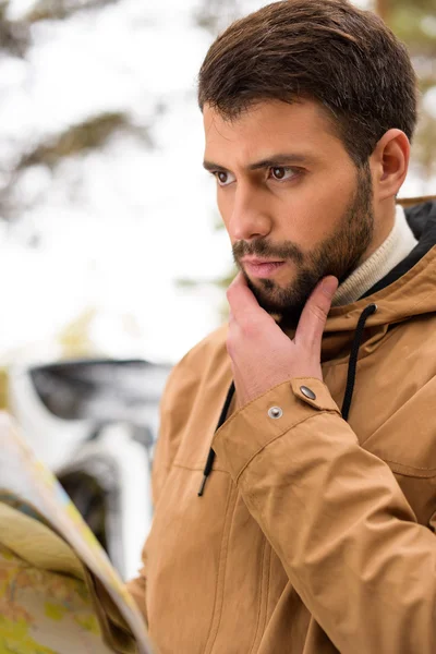 Uomo barbuto che tiene la mappa nella foresta — Foto stock