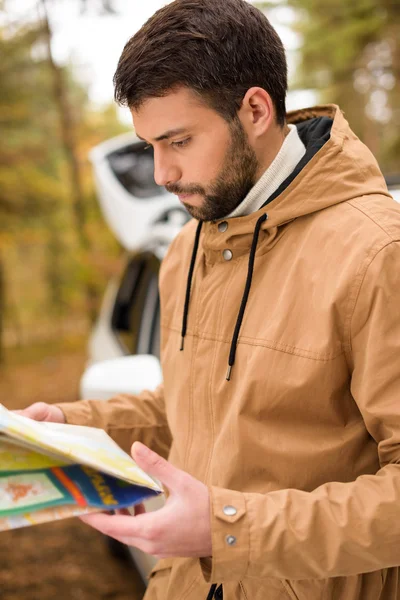 Bearded man holding map in forest — Stock Photo