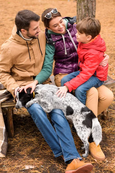 Feliz familia acariciando perro - foto de stock