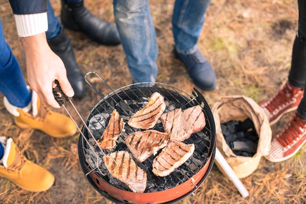 Pessoas que cozinham carne na grelha de carvão — Fotografia de Stock