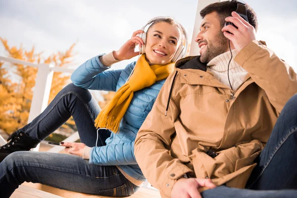 Joyeux jeune couple dans les écouteurs — Photo de stock