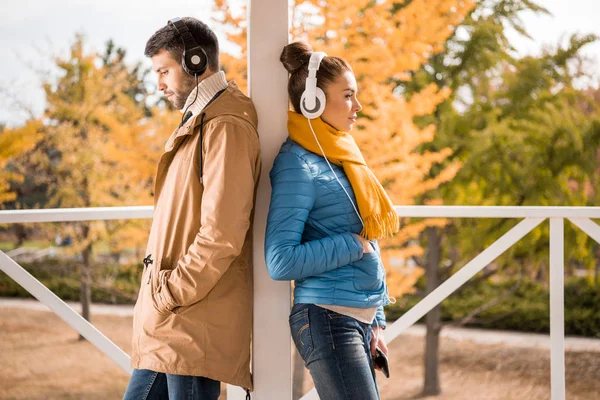 Joven hombre y mujer de pie en los auriculares - foto de stock