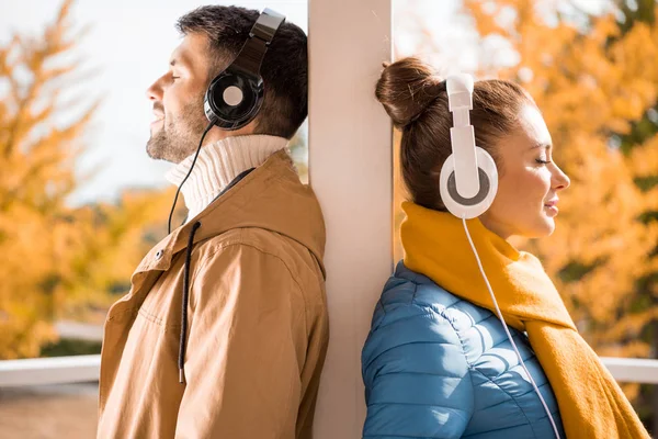 Joven hombre y mujer de pie en los auriculares - foto de stock