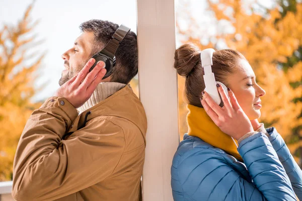 Joven hombre y mujer de pie en los auriculares - foto de stock