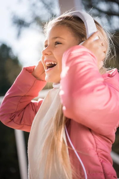 Lächelndes kleines Mädchen mit weißen Kopfhörern — Stockfoto