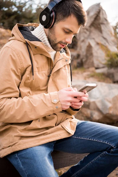 Homem em fones de ouvido segurando smartphone — Fotografia de Stock