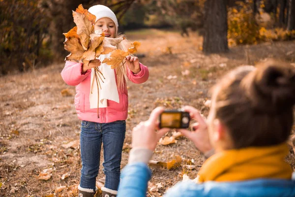 Мать фотографирует дочь в осеннем парке — стоковое фото