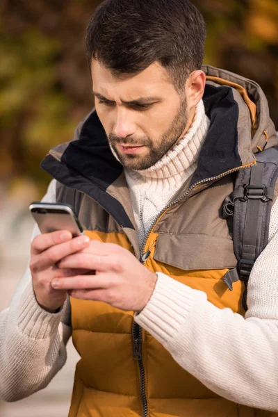 Nachdenklicher junger Mann schaut aufs Smartphone — Stockfoto