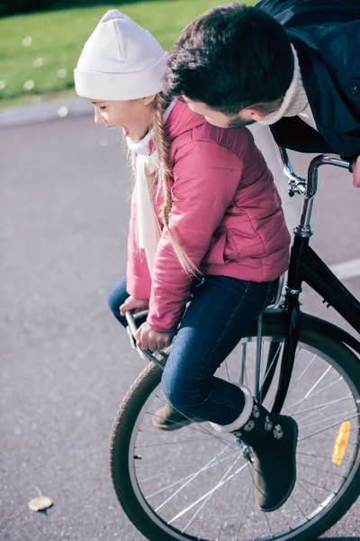 Father carrying smiling daughter on bicycle — Stock Photo