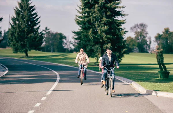 Happy family riding bicycles in park — Stock Photo