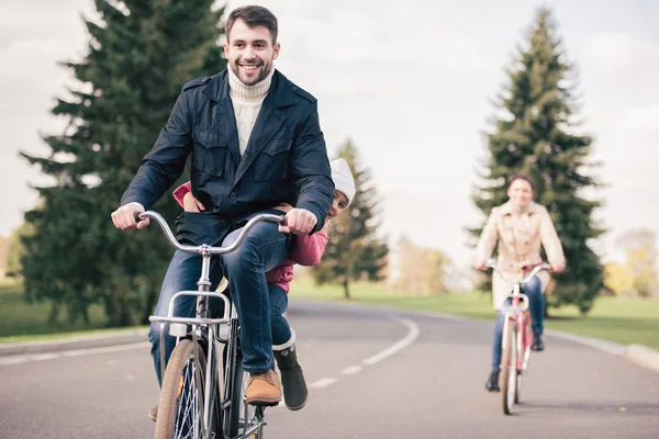 Felice famiglia a cavallo biciclette nel parco — Foto stock