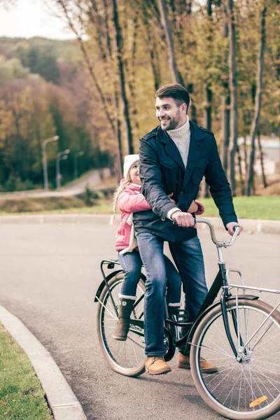 Father carrying daughter on bike — Stock Photo
