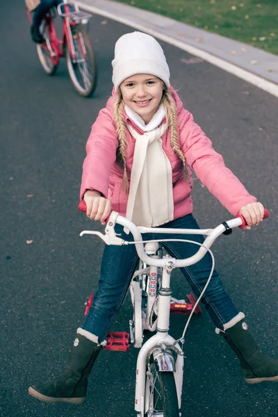 Adorable chica sonriente sentada en bicicleta - foto de stock