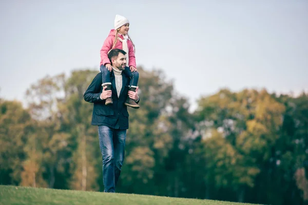 Sonriente padre llevando a su hija en hombros - foto de stock