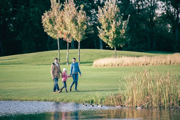 Familia feliz caminando cerca del lago - foto de stock