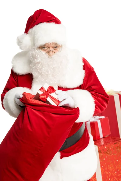 Papá Noel sacando el regalo de Navidad del saco - foto de stock