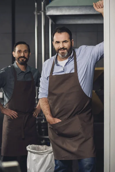 Male brewery workers in aprons — Stock Photo