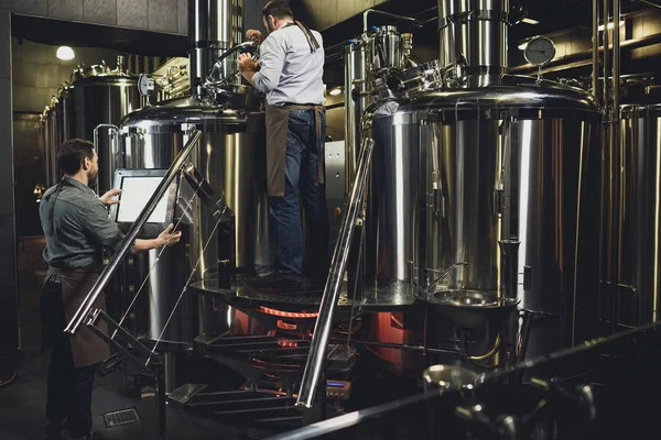 Cerveceros que trabajan con tanques - foto de stock