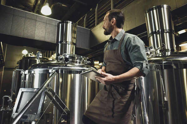 Працівник перевіряє обладнання на пивоварні — стокове фото