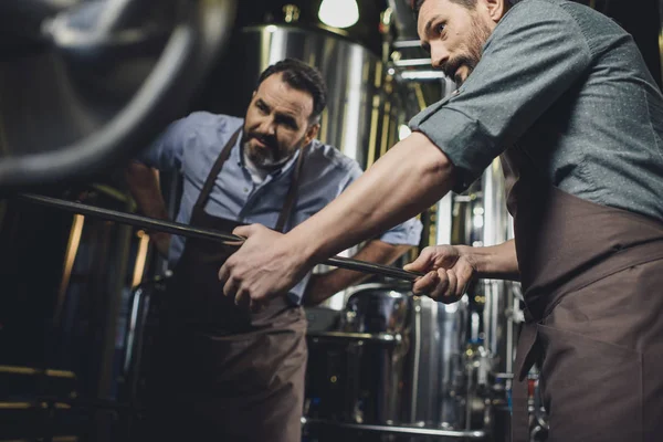 Cervejarias trabalhando com equipamentos industriais — Fotografia de Stock