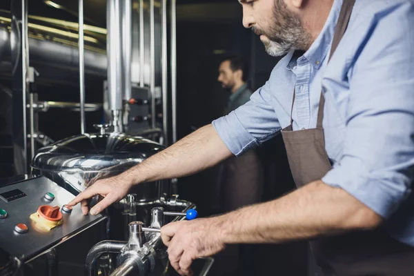 Cervejeiro trabalhando com equipamentos industriais — Fotografia de Stock