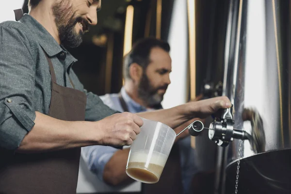 Trabalhador da cervejaria derramando cerveja — Fotografia de Stock