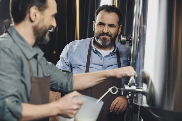 Trabajador cervecero vertiendo cerveza - foto de stock