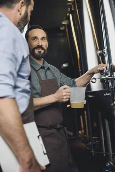 Trabajador cervecero vertiendo cerveza - foto de stock