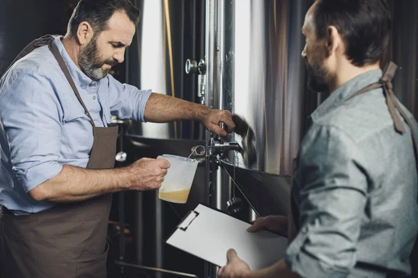 Trabajador cervecero vertiendo cerveza - foto de stock