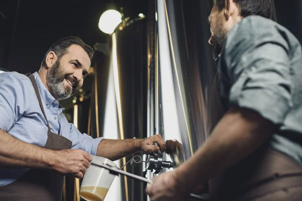 Trabajadores cerveceros vertiendo cerveza - foto de stock