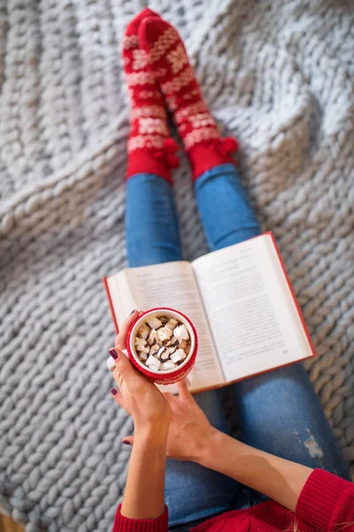 Mujer leyendo libro con bebida caliente - foto de stock