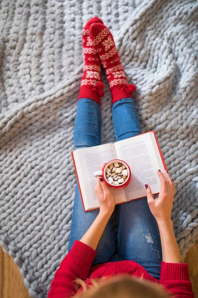 Woman reading book with hot drink — Stock Photo