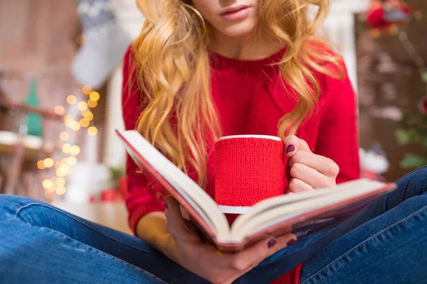 Mujer leyendo libro con bebida caliente - foto de stock