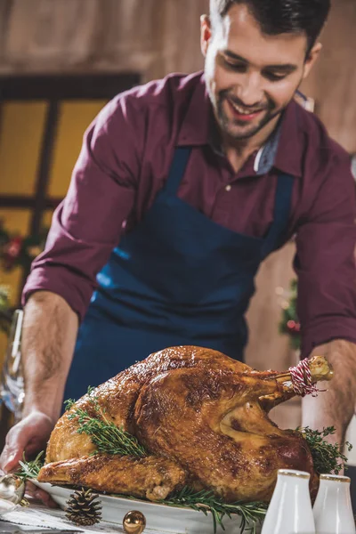 Man putting turkey on festive table — Stock Photo