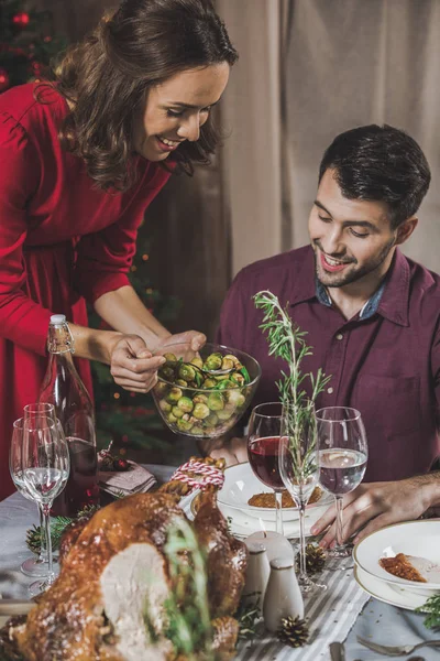 Mujer poniendo coles de Bruselas en el plato - foto de stock